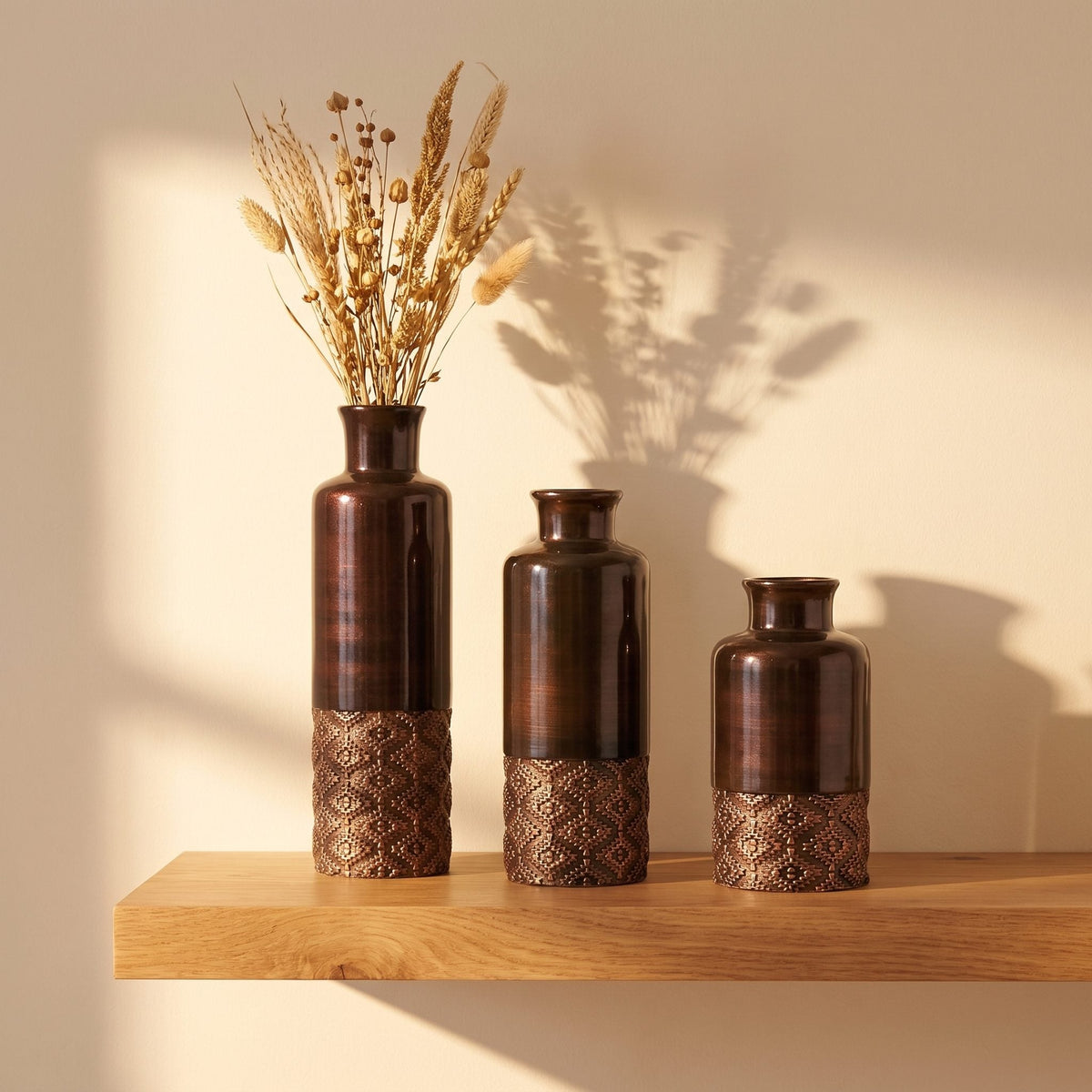 Three faceted ceramic vases in graduated heights grouped on a shelf
