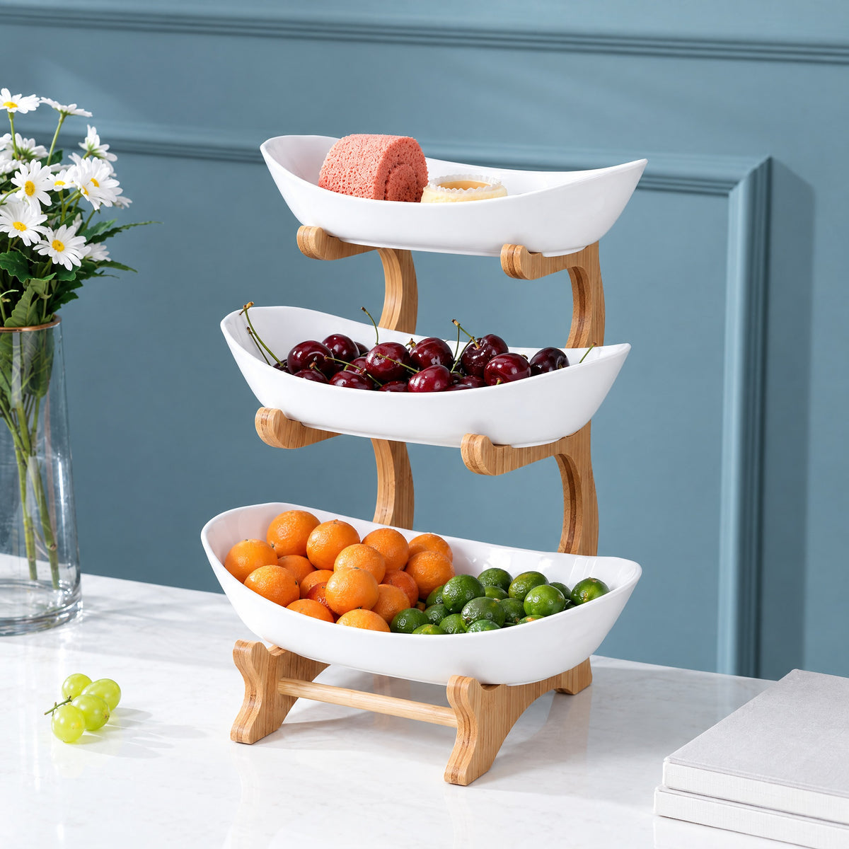 Three-tier fruit stand with white ceramic bowls on a natural bamboo frame, holding fruit on a kitchen counter