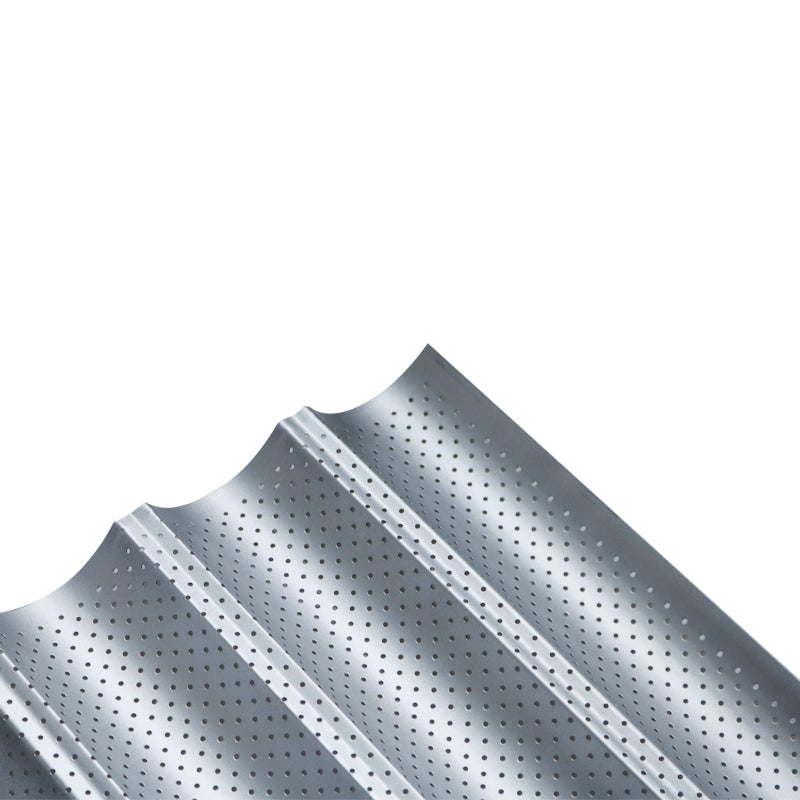 Perforated non-stick baguette baking pan with french bread loaves — scale view