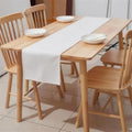 Warm white linen-weave table runner styled on a wooden dining table