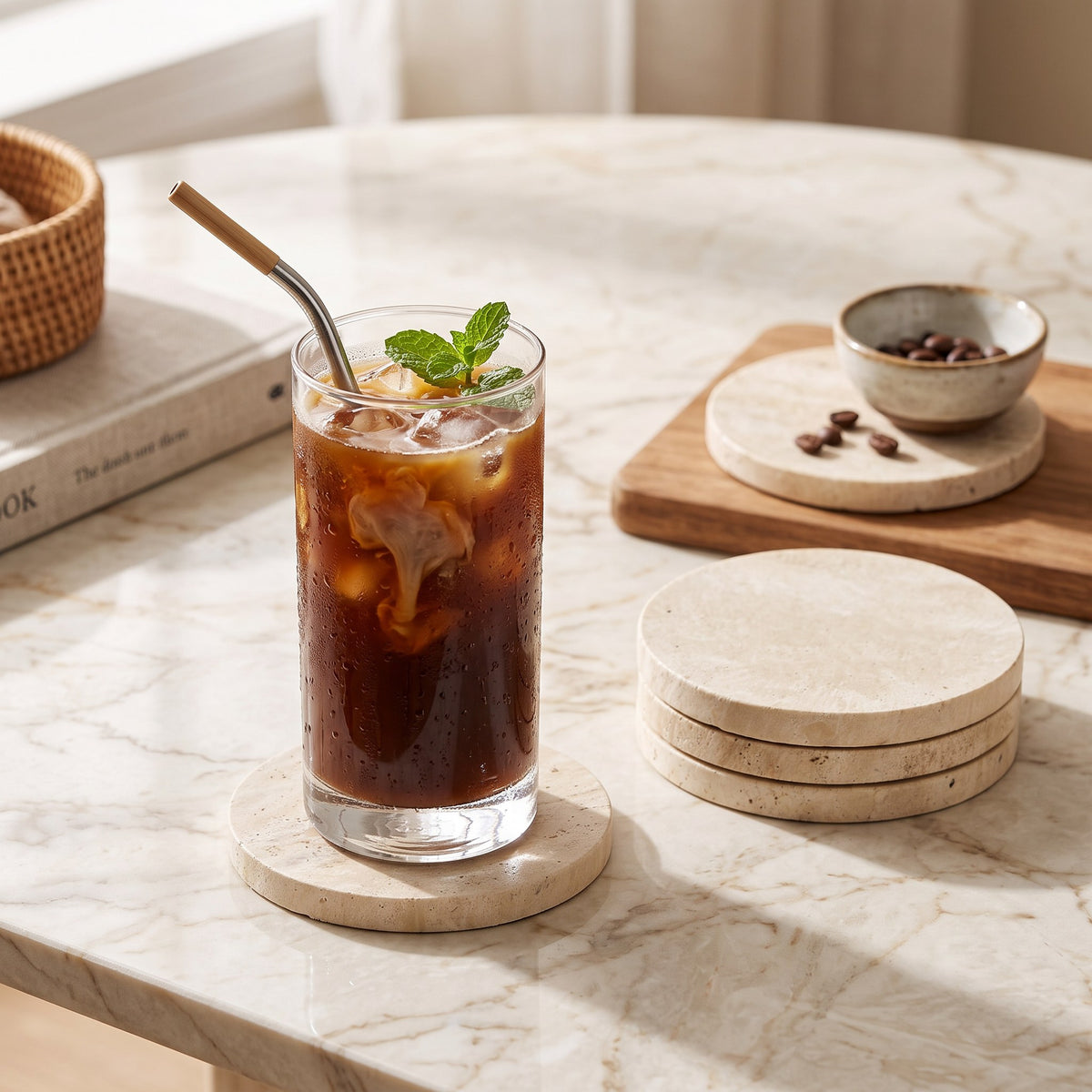 Natural travertine stone coasters on a marble coffee table with an iced coffee glass